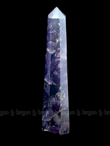 A tall, polished obelisk made of Amethyst, standing upright with smooth, transparent facets that catch and reflect light