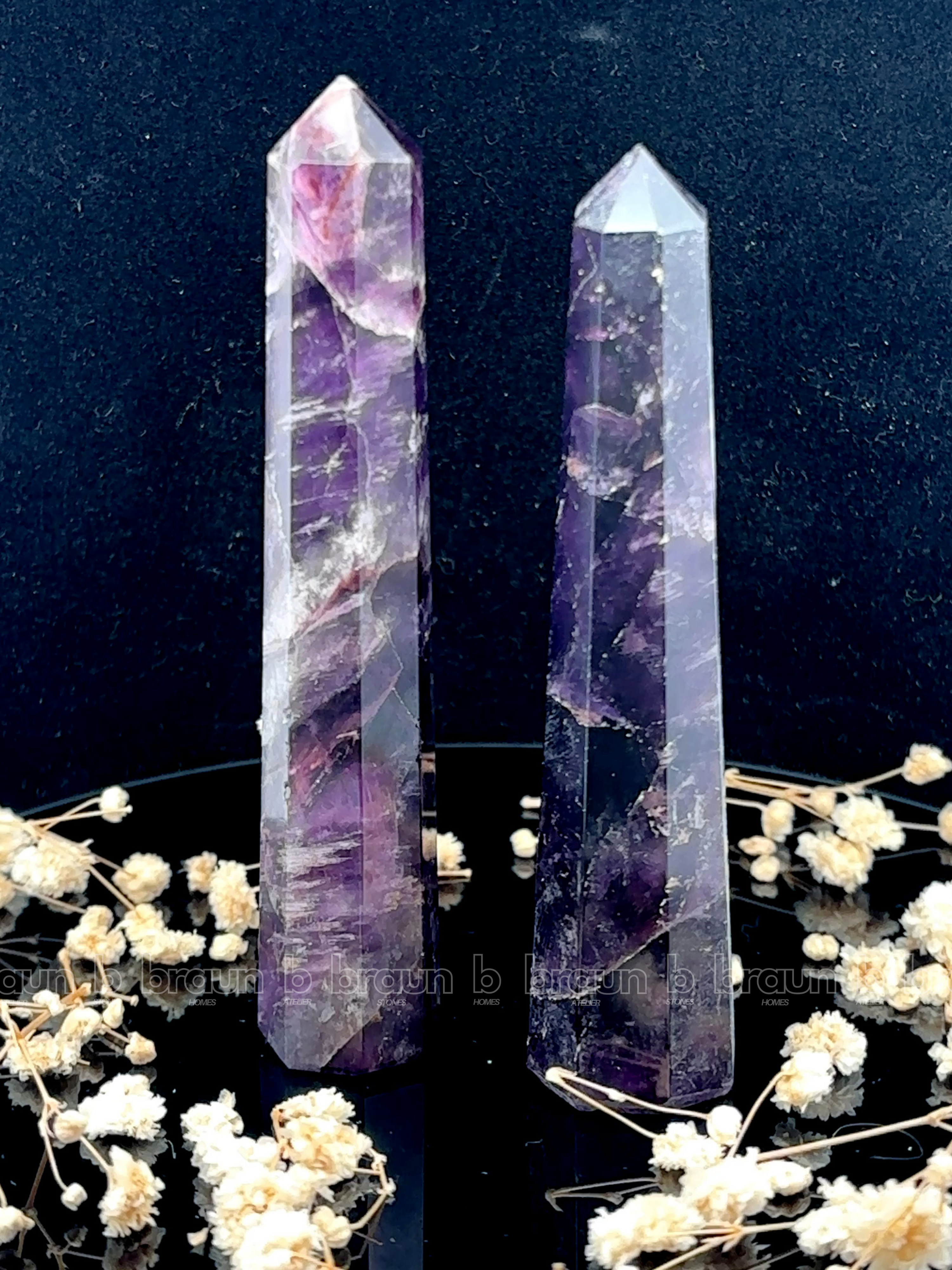A tall, polished obelisk made of Amethyst, standing upright with smooth, transparent facets that catch and reflect light