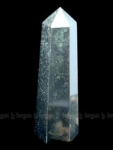 A tall, polished obelisk made of Black obsidian, standing upright with smooth, transparent facets that catch and reflect light