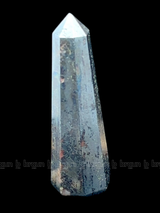 A tall, polished obelisk made of Hematite, standing upright with smooth, transparent facets that catch and reflect light