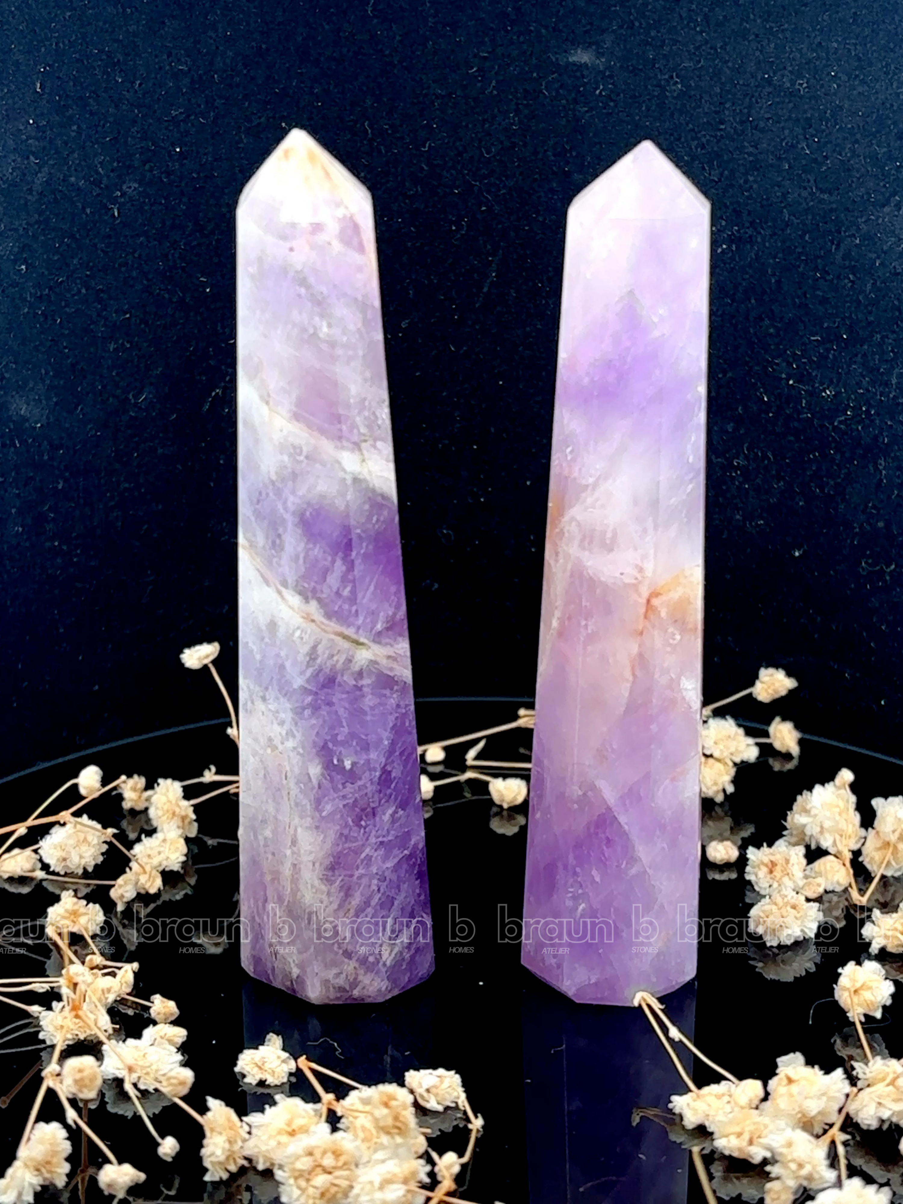 A tall, polished obelisk made of Lapidolite, standing upright with smooth, transparent facets that catch and reflect light