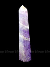 A tall, polished obelisk made of Lapidolite, standing upright with smooth, transparent facets that catch and reflect light
