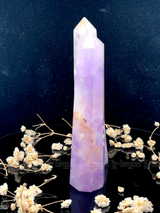 A tall, polished obelisk made of Lapidolite, standing upright with smooth, transparent facets that catch and reflect light