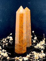 A tall, polished obelisk made of Mariam Jasper, standing upright with smooth, transparent facets that catch and reflect light