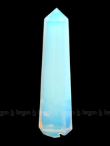 A tall, polished obelisk made of Opal, standing upright with smooth, transparent facets that catch and reflect light