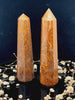 A tall, polished obelisk made of Mariam Jasper, standing upright with smooth, transparent facets that catch and reflect light