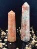 A tall, polished obelisk made of Sunstone, standing upright with smooth, transparent facets that catch and reflect light
