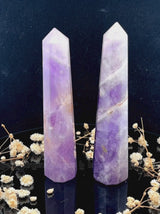 A tall, polished obelisk made of Lapidolite, standing upright with smooth, transparent facets that catch and reflect light