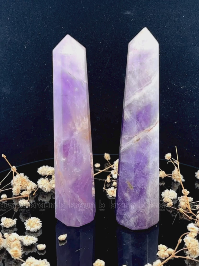 A tall, polished obelisk made of Lapidolite, standing upright with smooth, transparent facets that catch and reflect light