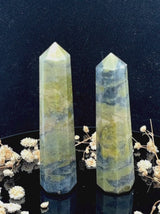 A tall, polished obelisk made of Vasonite, standing upright with smooth, transparent facets that catch and reflect light