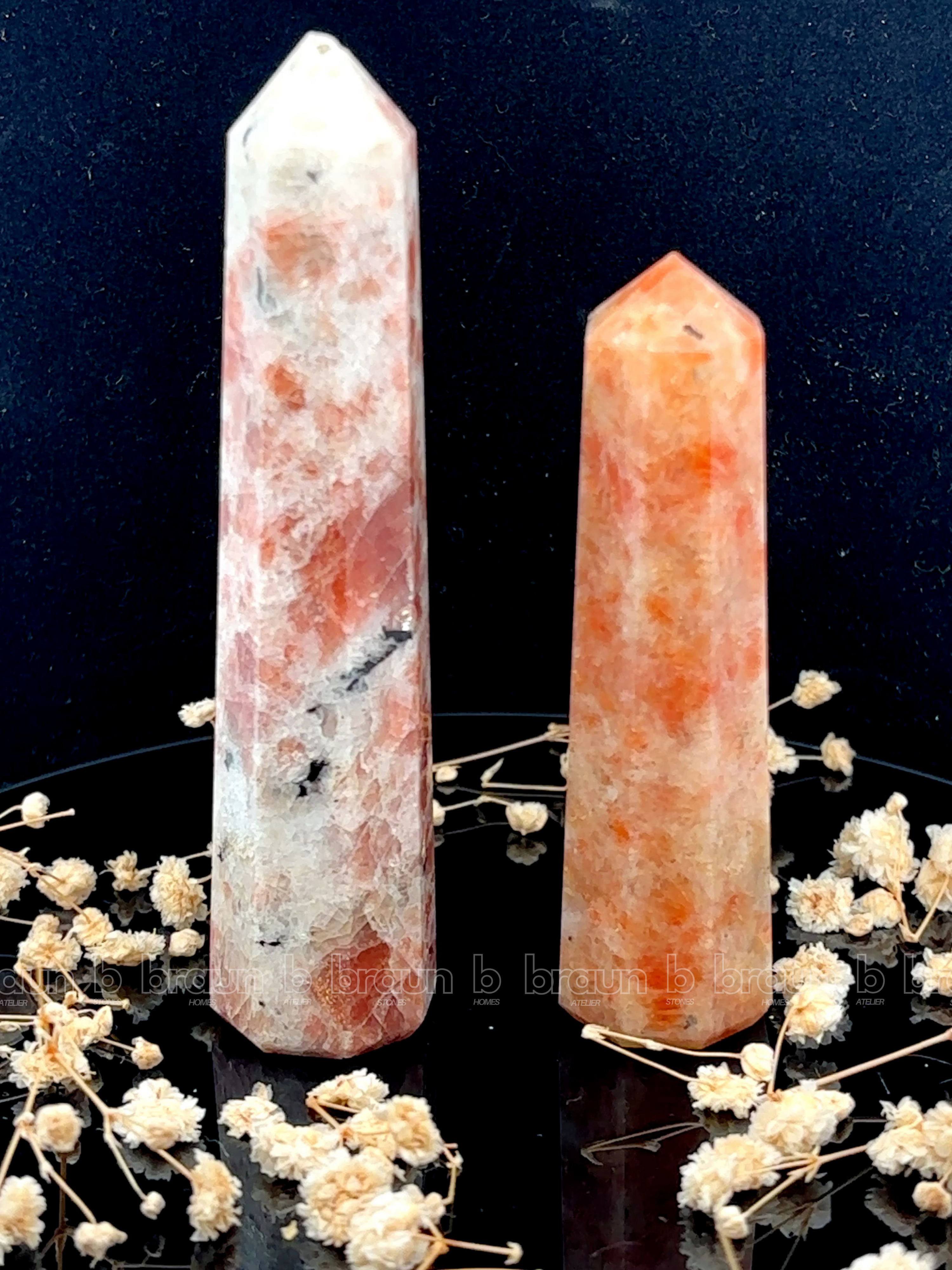 A tall, polished obelisk made of Sunstone, standing upright with smooth, transparent facets that catch and reflect light