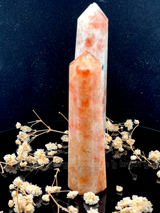 A tall, polished obelisk made of Sunstone, standing upright with smooth, transparent facets that catch and reflect light