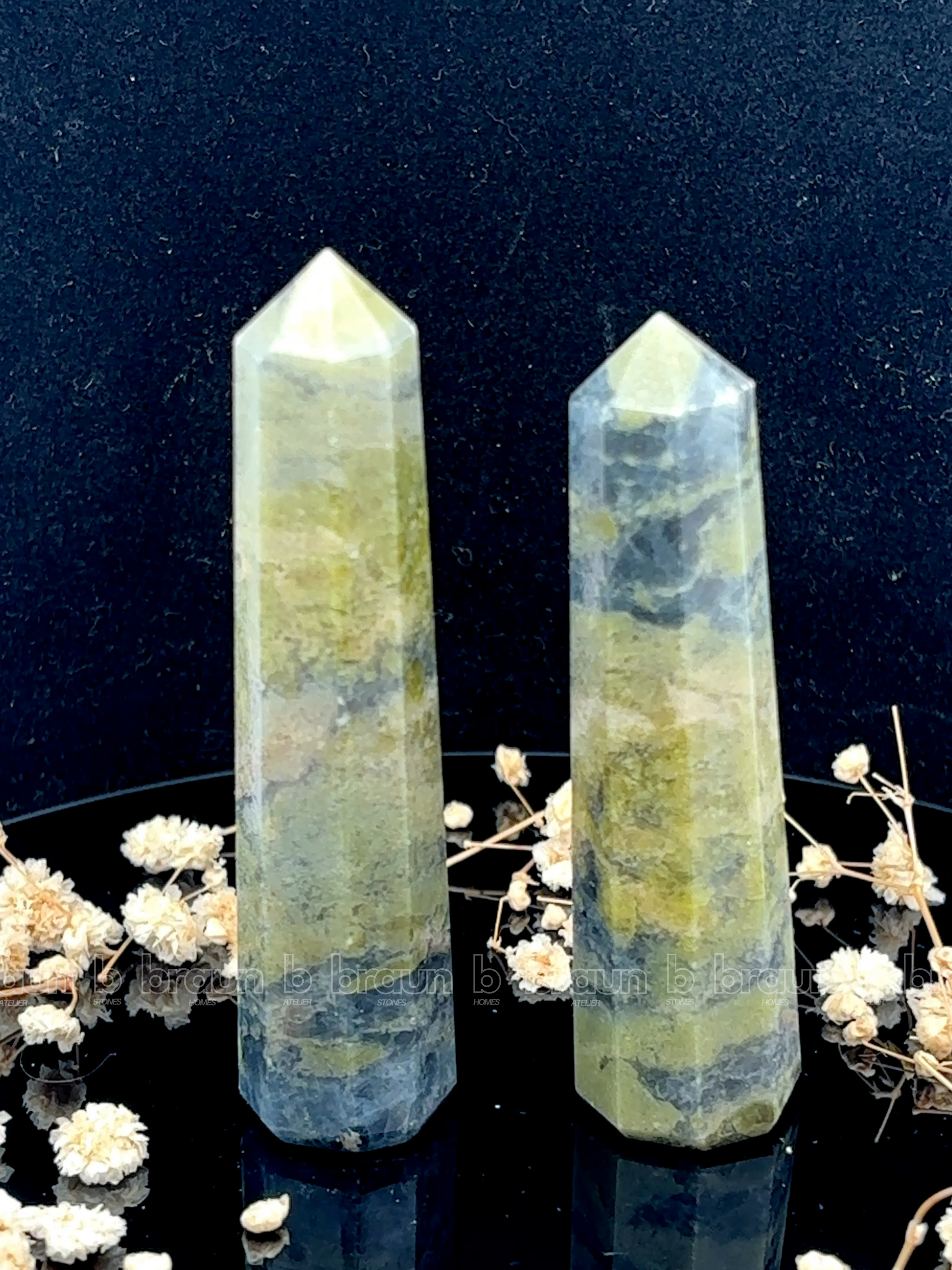 A tall, polished obelisk made of Vasonite, standing upright with smooth, transparent facets that catch and reflect light