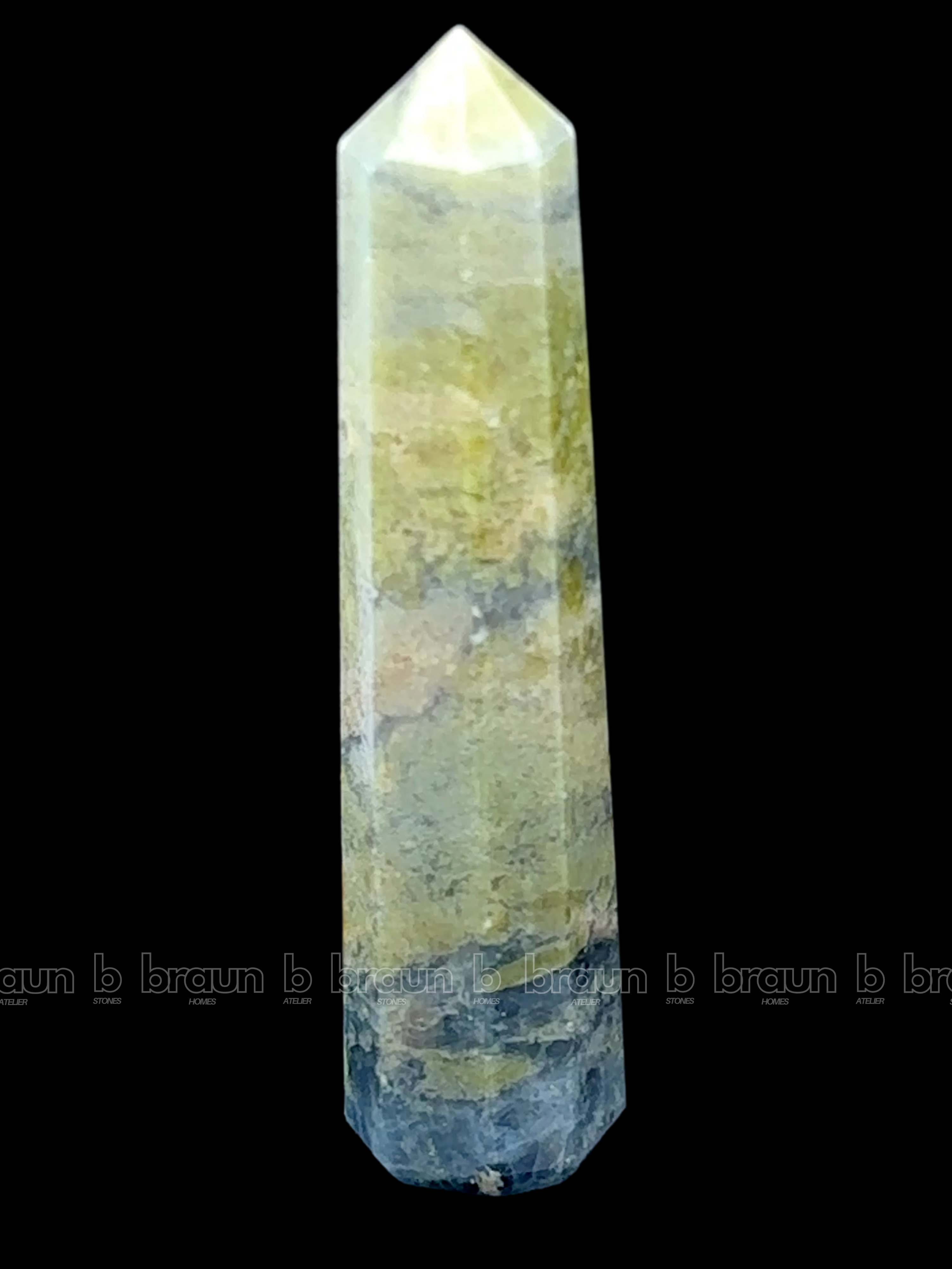 A tall, polished obelisk made of Vasonite, standing upright with smooth, transparent facets that catch and reflect light